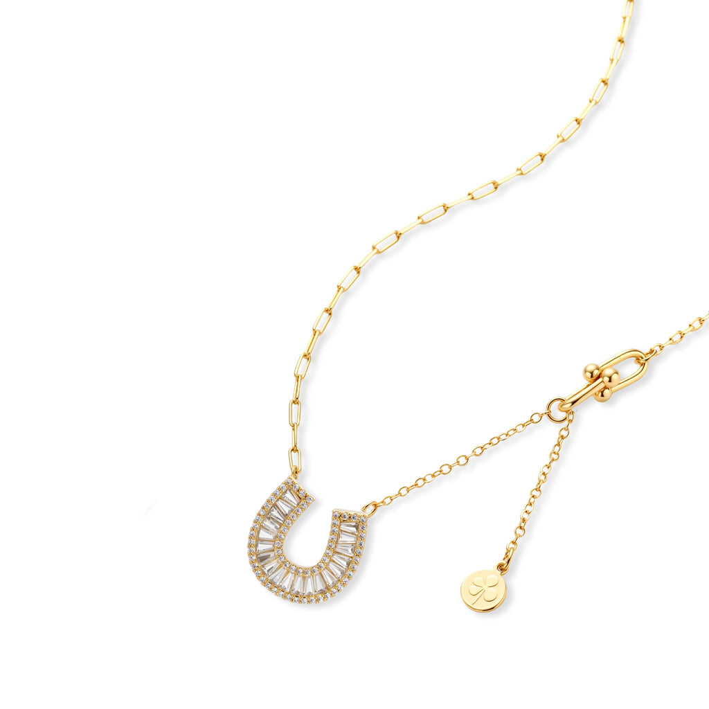 Sparkling horseshoe-shaped jewelry set with AAA cubic zirconia in gold-plated and white gold finishes on cream background.