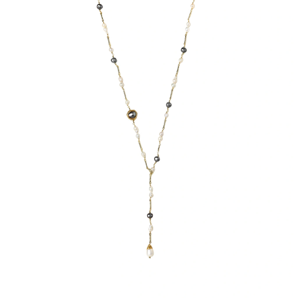 Y-shaped gold-plated necklace with white and gray freshwater pearls on cream background, showing adjustable drop design.
