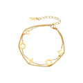 Double-layer gold-plated bracelet with quatrefoil and star charms on cream background, 18K gold finish.