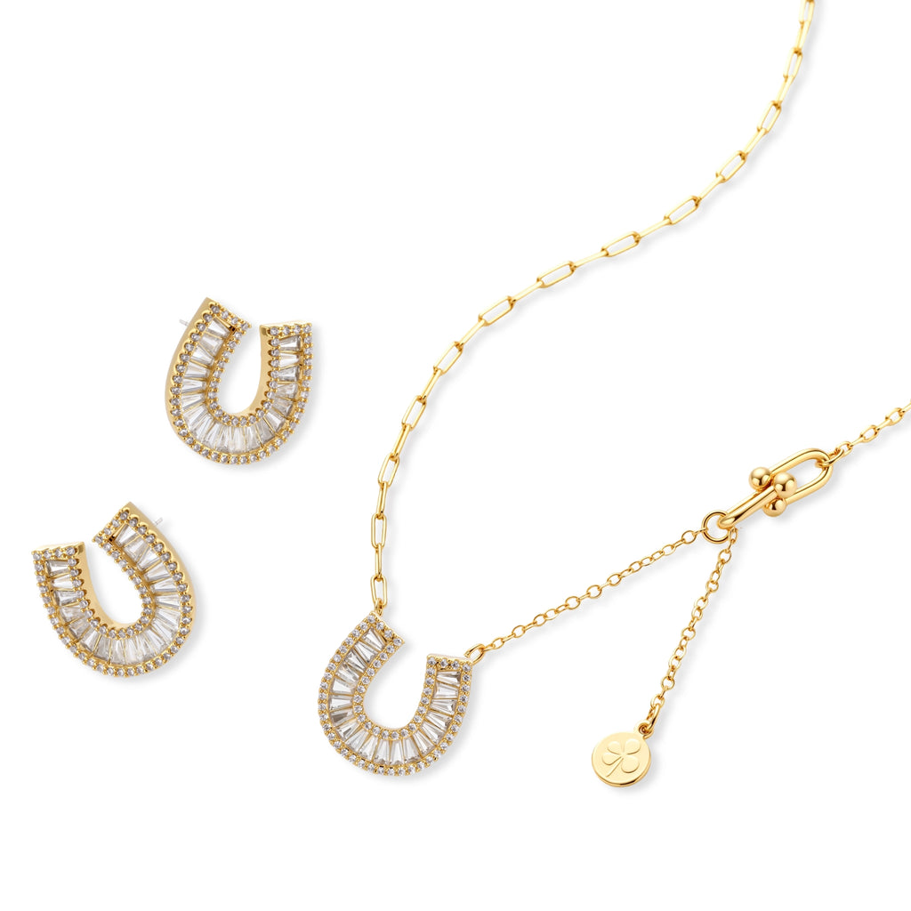 Sparkling horseshoe-shaped jewelry set with AAA cubic zirconia in gold-plated and white gold finishes on cream background.